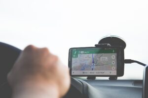 Smartphone displaying GPS navigation on a car dashboard while being held by a driver.